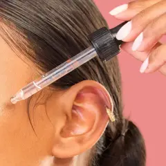 Dłoń z pipetką aplikuje serum na twarz. Odkryj metodę kanapkową efekty dla promiennej skóry.