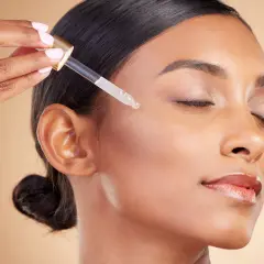 Kropla serum z witaminą A retinol na policzku kobiety, dla promiennej cery.