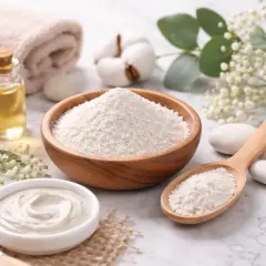 Kaolin co to? Biały proszek w drewnianej misce i na łyżce, obok kosmetyków i ręcznika. Idealny do domowych maseczek.
