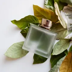 Szklana butelka perfum fougere otoczona jesiennymi liśćmi.
