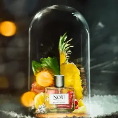 Perfumy NOU "Secret Blanc" w szklanej kopule, otoczone owocami i zielenią. Idealne miejsce, gdzie trzymać perfumy, by zachować ich świeżość.