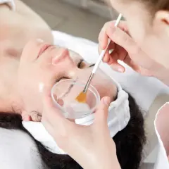 Kosmetyczka aplikuje na twarz pacjentki preparat z kwasem fitowym, który ma działanie rozjaśniające i złuszczające.