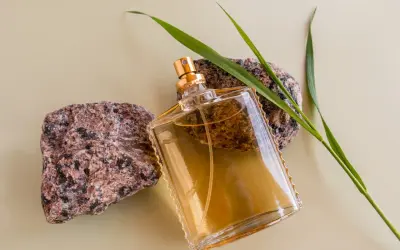 Szklana butelka z płynem, otoczona kamieniami i trawą. Klasyczne perfumy lat 90 męskie, które przywołują wspomnienia.