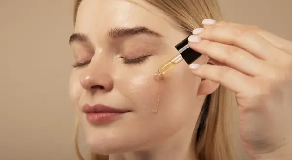 Kobieta aplikuje serum na twarz. Pamiętaj, retinol z czym nie łączyć, by uniknąć podrażnień.