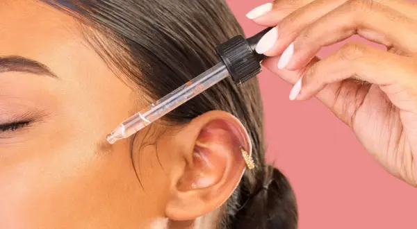 Dłoń z pipetką aplikuje serum na twarz. Odkryj metodę kanapkową efekty dla promiennej skóry.