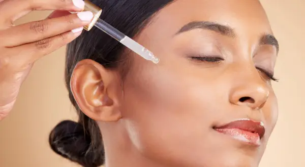 Kropla serum z witaminą A retinol na policzku kobiety, dla promiennej cery.