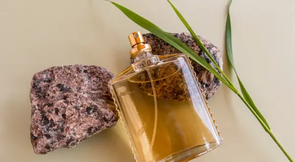 Szklana butelka z płynem, otoczona kamieniami i trawą. Klasyczne perfumy lat 90 męskie, które przywołują wspomnienia.