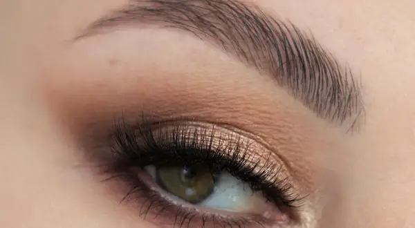 Oko z perfekcyjnym makijażem ślubnym smoky eyes, podkreślone długimi rzęsami i subtelnym cieniem w odcieniach brązu i złota.