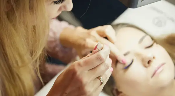 Profesjonalne szkolenie laminacja brwi i rzęs. Stylistka pracuje nad brwiami klientki, tworząc idealny kształt.