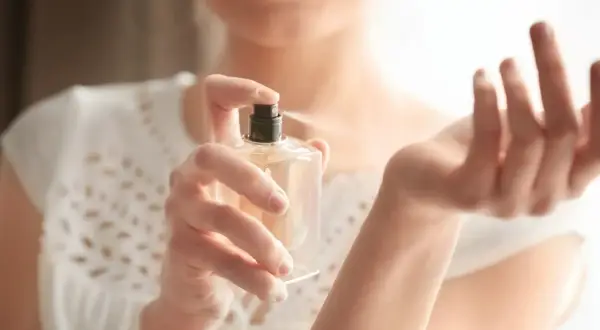 Kobieta aplikuje perfumy na nadgarstek. Zastanawiasz się, ile razy psikać się perfumami, by zapach był subtelny, ale wyczuwalny?