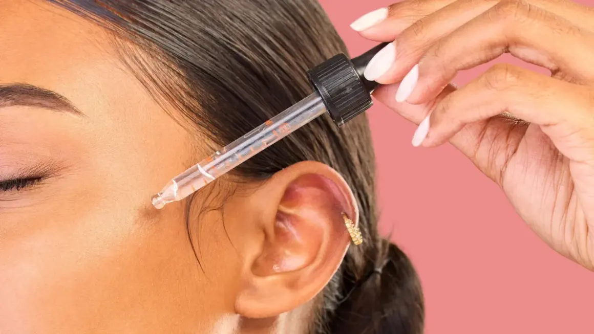 Dłoń z pipetką aplikuje serum na twarz. Odkryj metodę kanapkową efekty dla promiennej skóry.