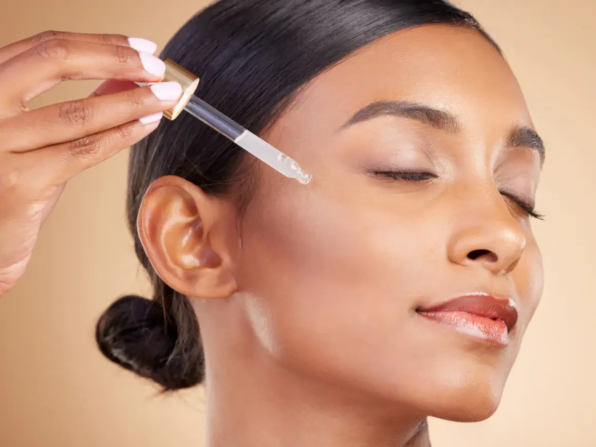Kropla serum z witaminą A retinol na policzku kobiety, dla promiennej cery.