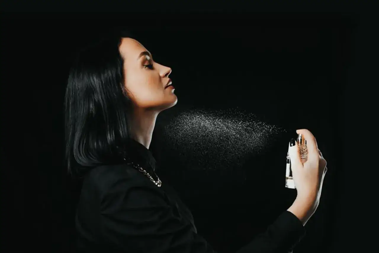 Kobieta rozpyla perfumy na szyję, pokazując, jak używać perfum.
