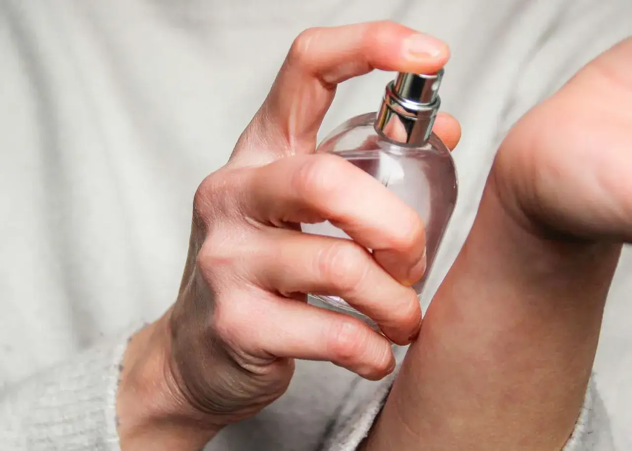 Dłoń aplikuje perfumy na nadgarstek. Zastanawiasz się, ile razy psikać się perfumami, by zapach był subtelny, ale wyczuwalny?