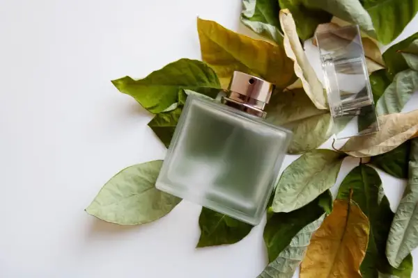 Szklana butelka perfum fougere otoczona jesiennymi liśćmi.