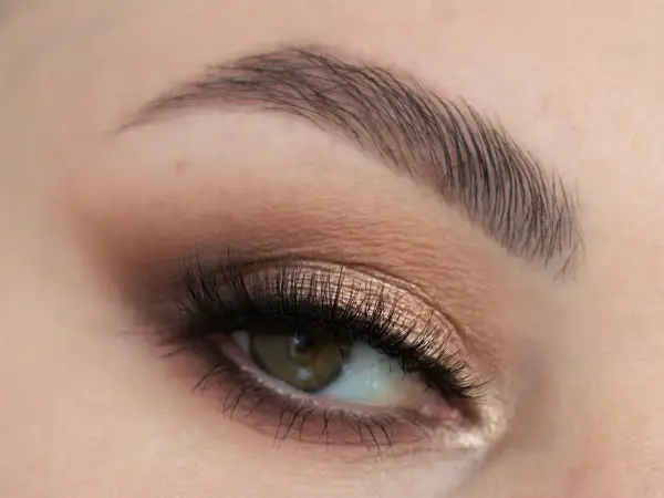 Oko z perfekcyjnym makijażem ślubnym smoky eyes, podkreślone długimi rzęsami i subtelnym cieniem w odcieniach brązu i złota.