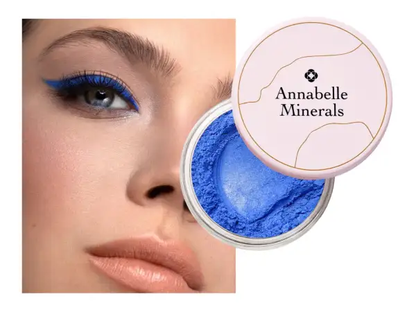 Oko podkreślone intensywnym, niebieskim eyelinerem. Obok słoiczek z sypkim, niebieskim cieniem Annabelle Minerals.